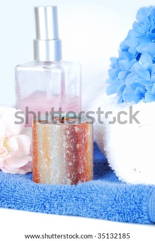 Wonderful handmade assertive candle making nice spa composition for bathroom with towel, perfume mist and real blue flowers.