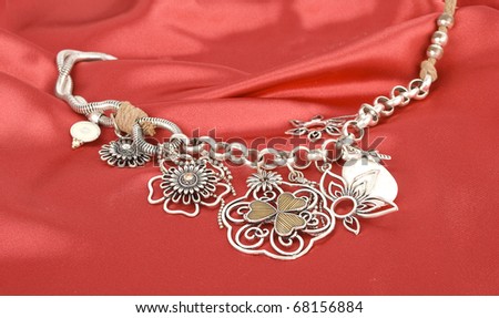 Silver necklace  with flowers on the red silk background.