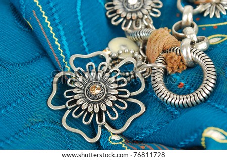 Silver necklace with flowers on the blue fabric  in East style background.