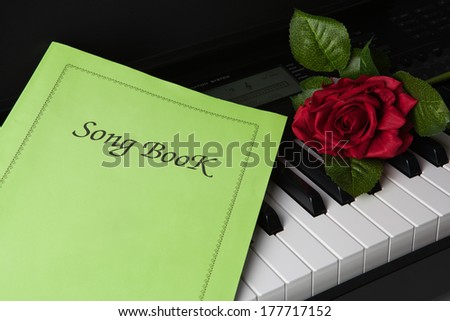 Piano keys, song book,and rose flower