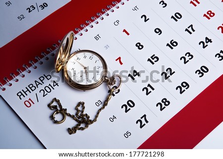 Gold pocket watch with wall calendar close-up