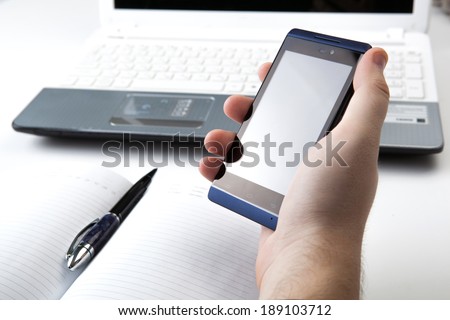 human fingers near the notebook keyboard and smartphone close-up