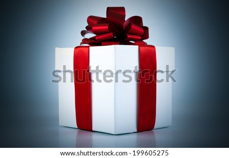 White gift box with red ribbon and bow on blue background