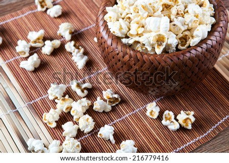 lot of salt popcorn into a bamboo bowl close up