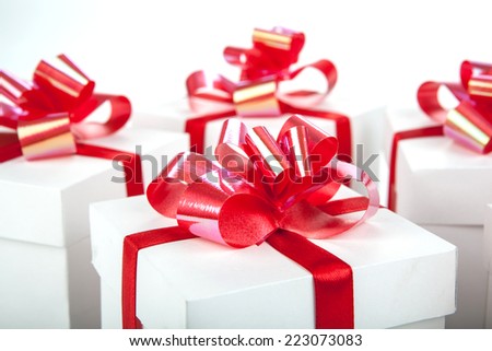 White gift boxes with red ribbons and bows on gray