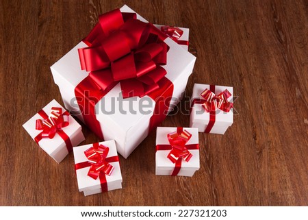 one large white gift box and white gift boxes on a wood background