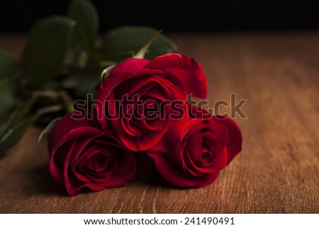 bouquet of roses lying on a wooden table on a black background close up