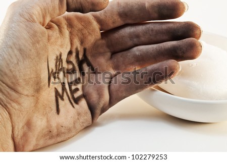 Close up of dirty caucasian bare hand with wash me written on palm and soap in background isolated on white background.