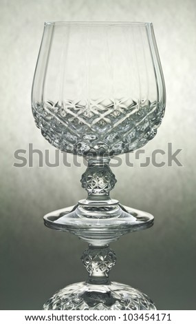 Close up of empty crystal cognac stem glass with reflection and back lighting.