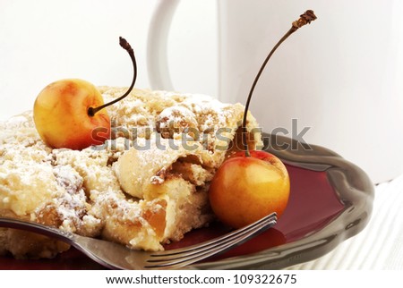 Delicious fresh coffee cake served with fresh rainier cherries on red plate with silver fork on white background.