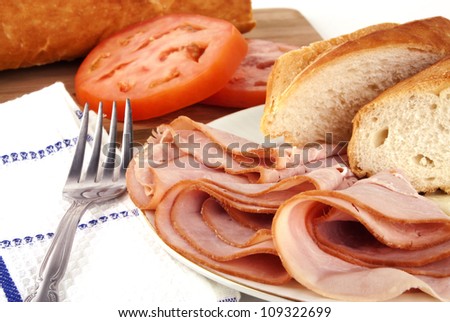 Delicious lunch time spread with ham, bread, cheese and tomatoes with silver fork