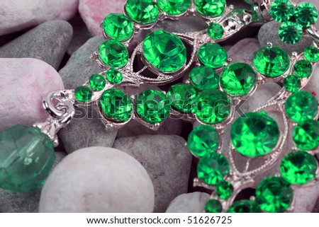 Green colored precious stone jewelery on stones background