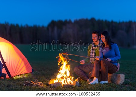 Camping night couple cook by campfire backpack in romantic countryside