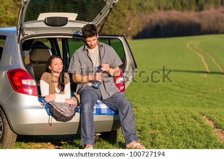 Happy camping couple lying inside car summer sunset countryside