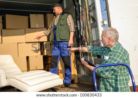 Two male movers unload furniture and boxes  from moving truck