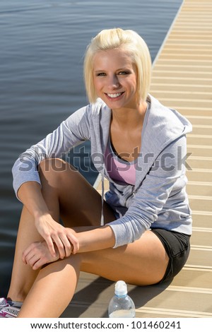 Smiling sport woman relax on pier water sunny day