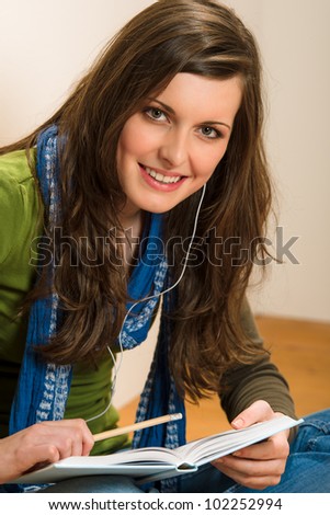 Portrait of student teenager woman with book listen music