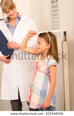 Pediatrician measure height of young girl at medical office