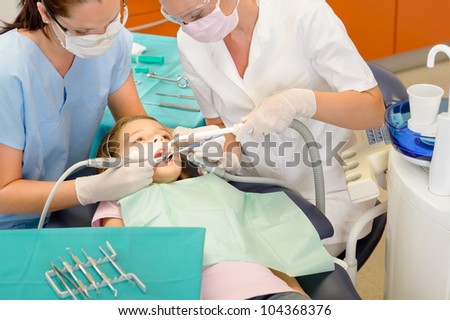 Dentist and assistant with little girl patient  at stomatology clinic
