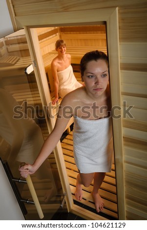 Exhausted woman leaving sauna in healthy spa center