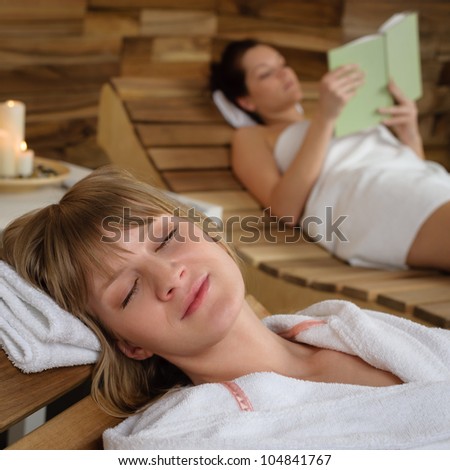 Relaxed young woman resting on wooden chair at luxury spa