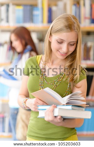 Happy female blonde student at library with books high school
