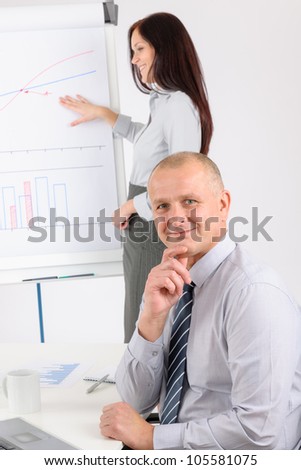 Giving presentation mature executive during meeting woman pointing flip chart