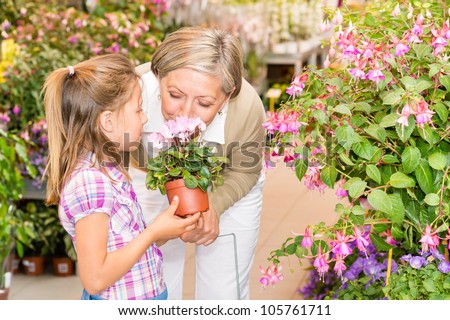 Grandmother and granddaughter holding pink potted flower at garden center