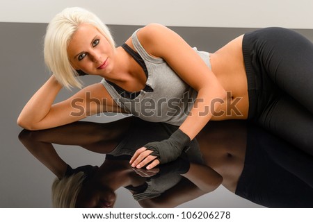 Female kickboxer laying down on black plexiglass at fitness studio