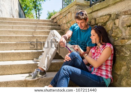 Young couple looking city map sunny day sitting stairs together