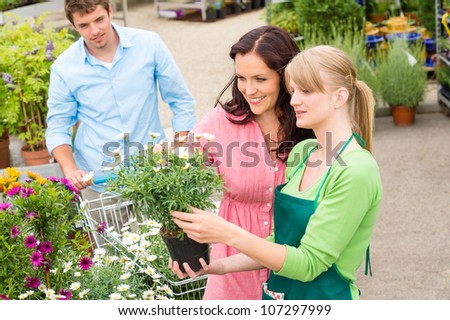 Florist at garden centre selling potted flowers to young couple
