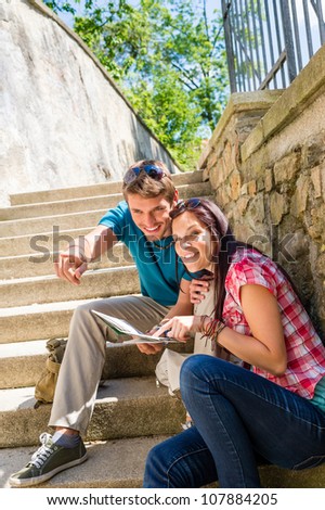 Young couple on holiday with city map point direction smiling