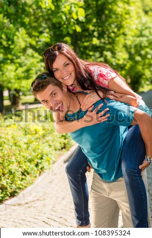 Happy couple piggyback hugging in summertime park love smiling fun