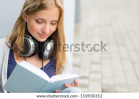 Student reading a book outside of university woman happy study
