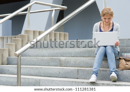 Teenage girl working on laptop computer happy student on stairs