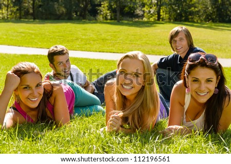 Students laying on grass in park campus smiling relaxing happy