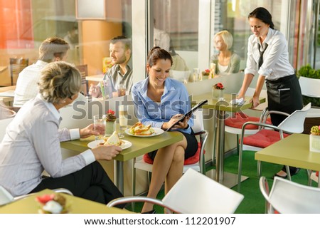 Businesswomen talking business in lunch break cafe happy working showing