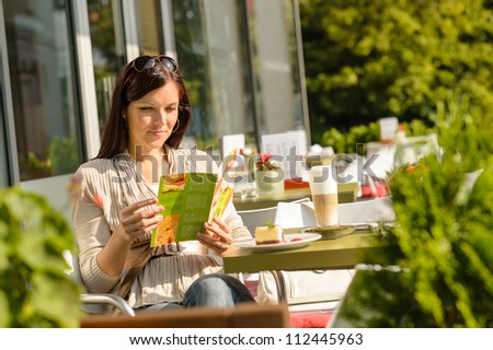 Woman looking at menu sitting cafe bar terrace choice dessert