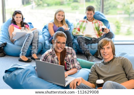 Students sitting on beanbags study room high-school teens happy