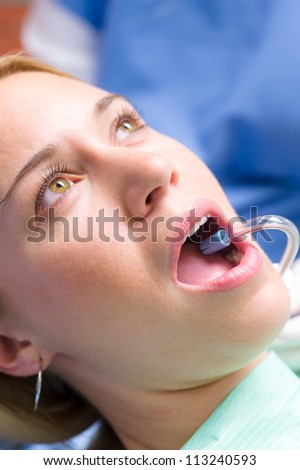 Woman patient at dentist open mouth with suction hose close-up
