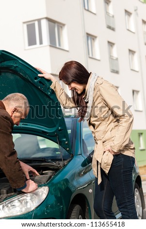 Man working on repairing a woman\'s car breakdown problem broken
