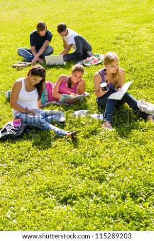 Students studying sitting in the park teens reading writing laptop