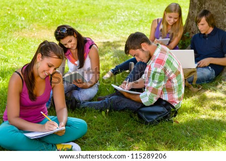 Students sitting in park studying reading writing teens campus schoolyard