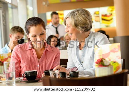 Mother and daughter relaxing in a cafe women restaurant happy