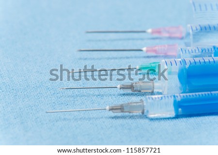 Hypodermic needles injections on blue medical cloth sorted in line