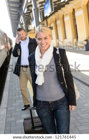 Woman in train station man on cellphone smiling commuters transport