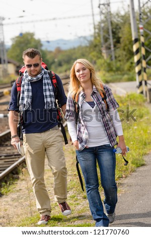Couple walking with backpack in train station happy woman man