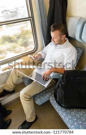 Man texting on phone holding laptop train commuter work journey