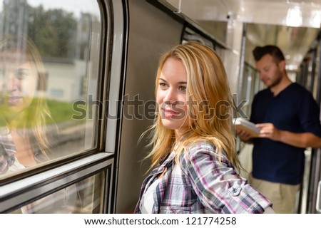 Woman looking out the train window smiling man reading book