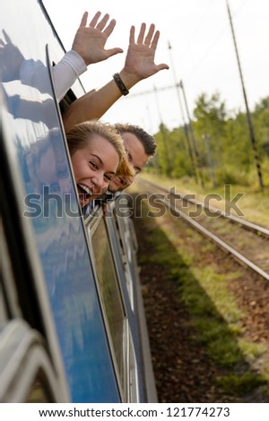 Couple waving with heads out train window enthusiastic woman man